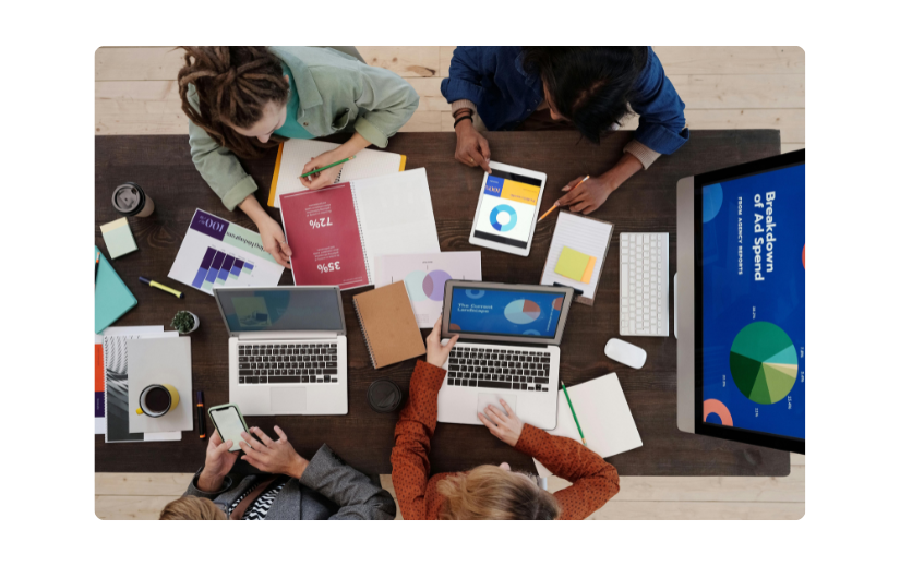 Top view of a team discussing dropshipping trends for 2025 with laptops and marketing materials. 